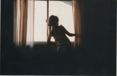 film photo of young girl in window