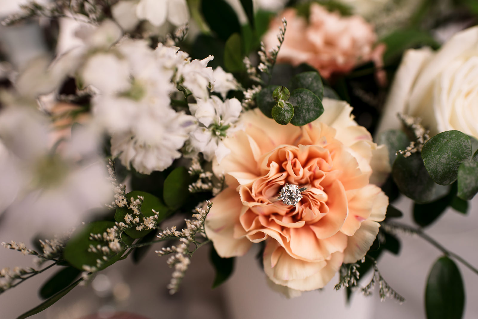beautiful solitaire engagement ring sits in floral bouquet