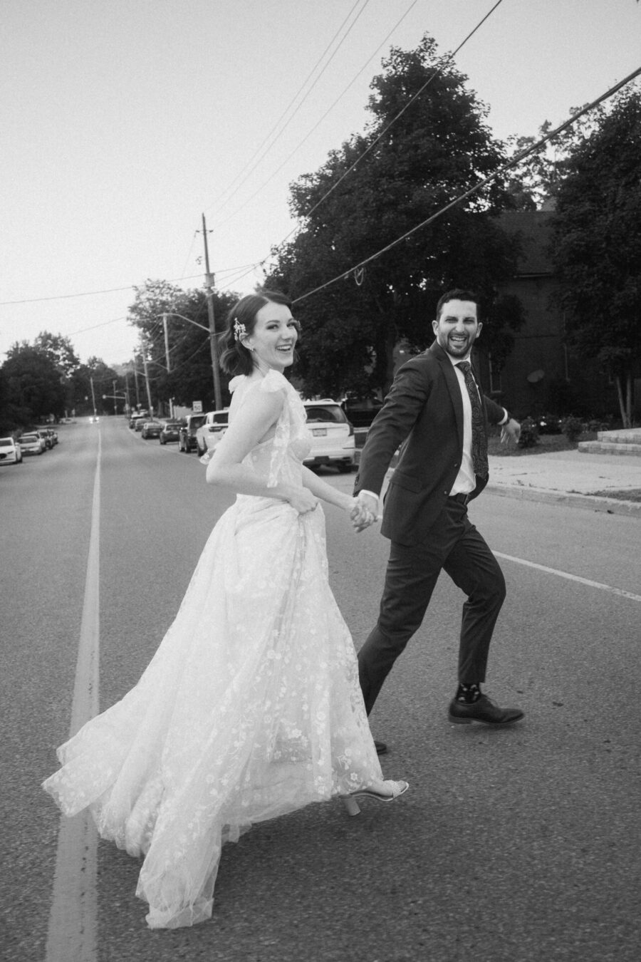 bride and groom run across a road together